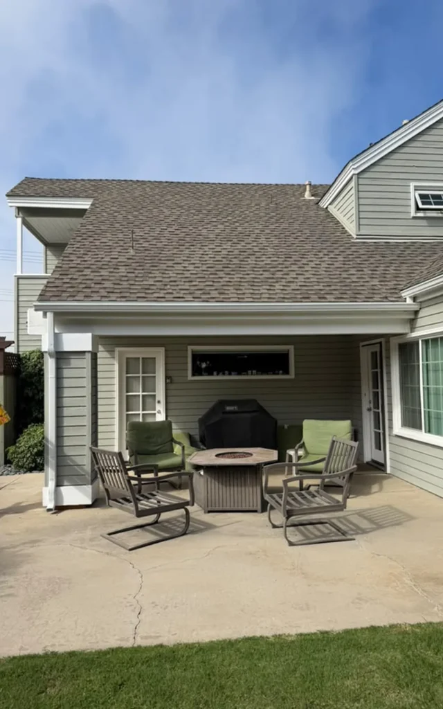 White 5-inch K-style gutter across the covered patio roof, with a matching downspout on the left beside the outdoor seating area.